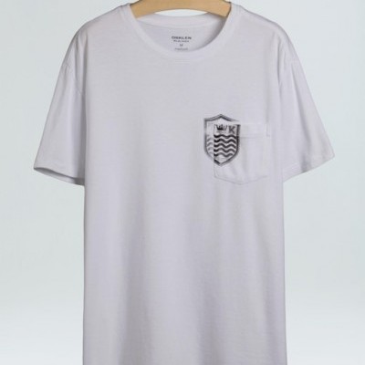 T-shirt branca com bolso e escudo estampado no peito pendurada em cabide de madeira