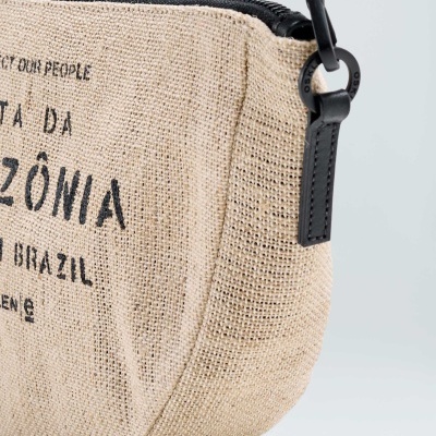 Bolsa pequena bege com fecho preto e texto impresso.