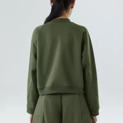 Casaco e calças verdes vistos de trás em fundo claro