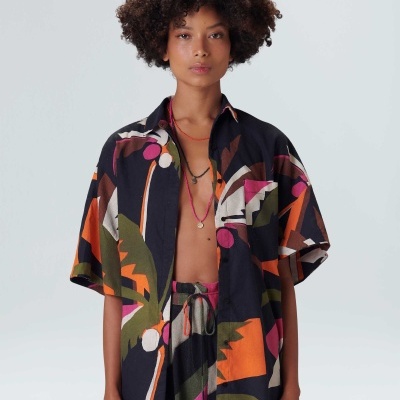 Camisa colorida de padrão abstrato com mangas curtas e gola clássica, usada aberta.