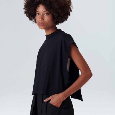 Mulher com blusa preta sem mangas e saia preta com bolso em fundo claro