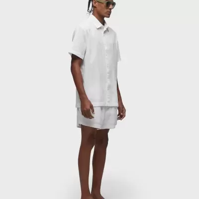 Homem com roupa branca e sandálias pretas em fundo branco