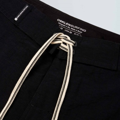 Calções pretos com cordão branco e etiqueta OSKLENSURFING