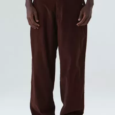 Calças largas castanhas escuras com bolso lateral e botão frontal, usadas com sapatos pretos e t-shirt branca