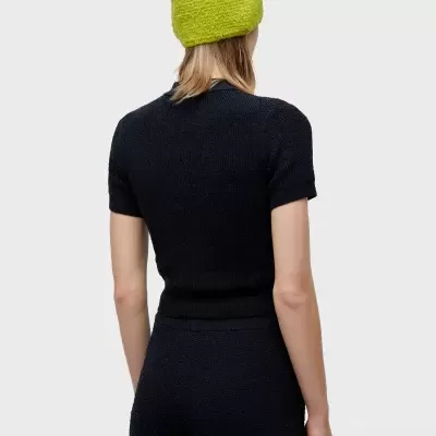 Pessoa de costas com conjunto preto de malha e gorro verde-limão.