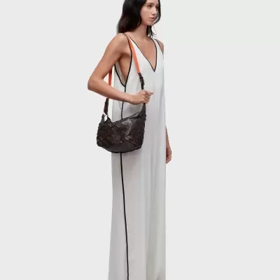 Mulher com vestido branco longo e bolsa tiracolo castanha