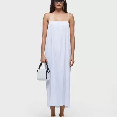 Mulher com vestido longo branco de alças finas e acessórios