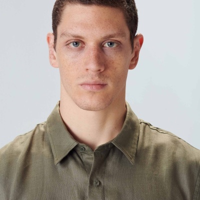 Homem com camisa verde-oliva em fundo cinza claro