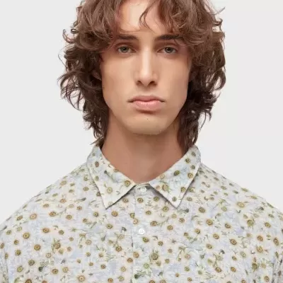 Camisa floral azul claro com pequenas margaridas amarelas e botões brancos.