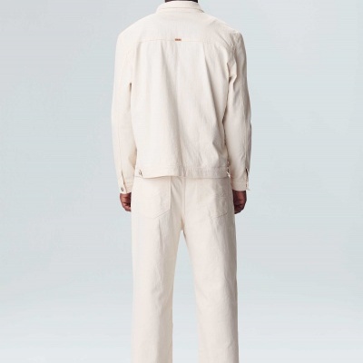 Conjunto casual branco/bege com casaco e calças largas, visto de costas.