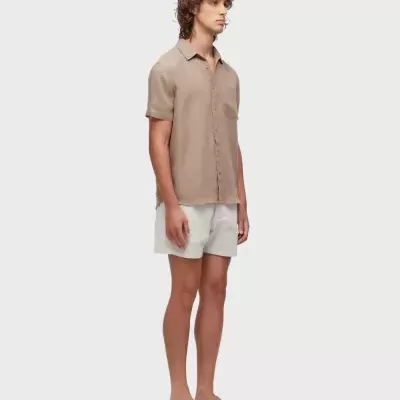 Homem com camisa bege, calções brancos e chinelos bege