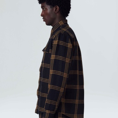 Camisa xadrez preta com linhas amarelas vista de lado em modelo