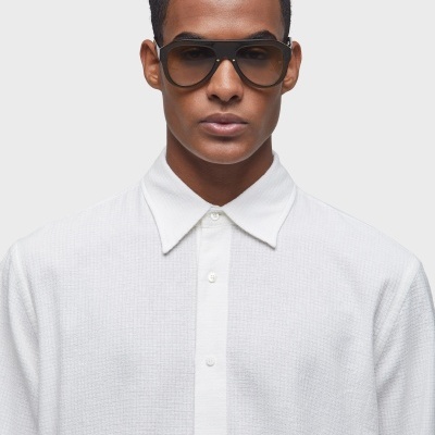 Modelo com óculos de sol de armação preta e camisa branca texturizada