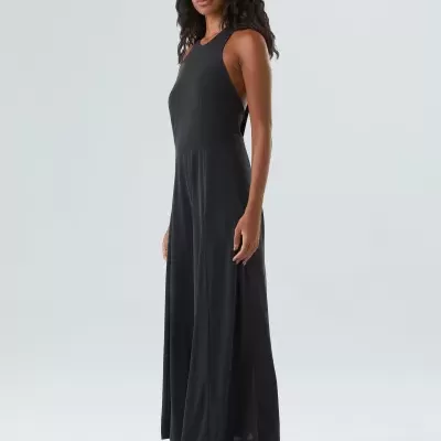 Modelo feminina com vestido preto comprido e sapatos pretos com sola branca.