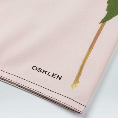 Pano rosa com estampa de folha verde e texto OSKLEN