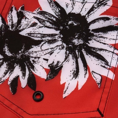 Pano têxtil vermelho com flores brancas e pretas e etiquetas OSKLENSURFING e símbolo de tridente
