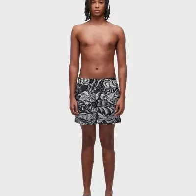 Homem com calções de banho preto e cinza com padrão floral