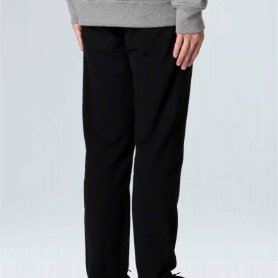 Calças pretas lisas de corte reto usadas com camisola cinzenta e sapatilhas pretas