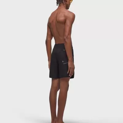 Modelo masculino de costas a usar calções pretos com bolso e óculos de sol amarelos.