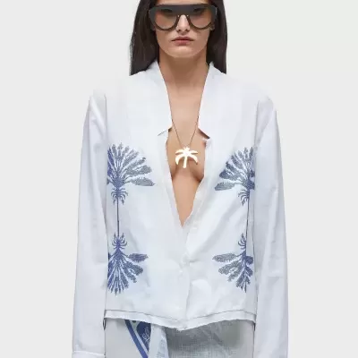 Blusa branca com padrão de folhagem azul e colar dourado, vista frontal