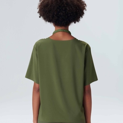 Pessoa vista de costas com camiseta e calças verdes e colar verde.