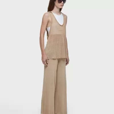 Conjunto feminino bege com colete e calças largas, t-shirt branca e sapatilhas brancas.