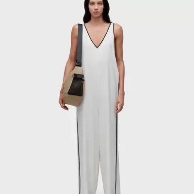 Mulher com macacão branco com risca preta e mochila bege e preta