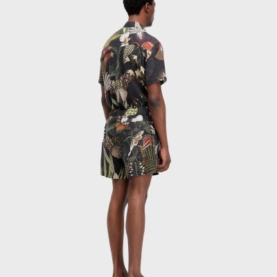 Homem de costas com camisa e calções com padrão floral escuro