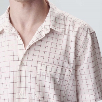 Camisa branca de manga curta com padrão quadriculado vermelho e bolso no peito.