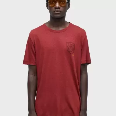 Homem vestido com t-shirt vermelha e calças amarelas num fundo branco