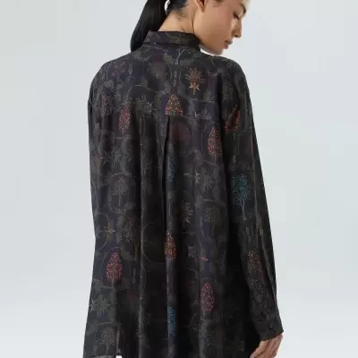 Camisa preta com padrão colorido de árvores vista por trás, usada por mulher