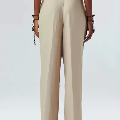 Calças bege femininas de cintura alta vistas de costas com sapatos e pulseiras.