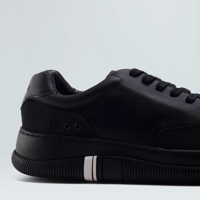 tênis desportivo preto com riscas brancas na sola