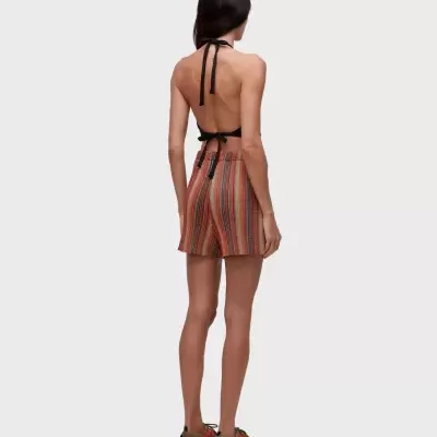 Mulher vestindo top preto, calções de riscas verticais e ténis castanhos com detalhes laranja