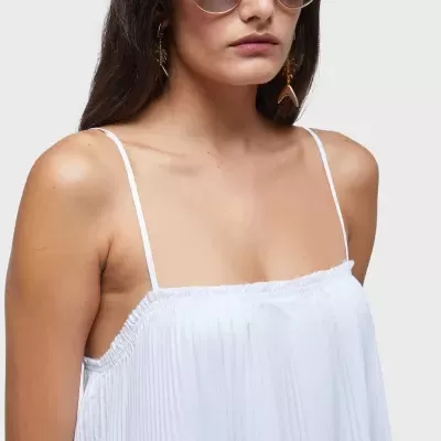 Mulher com vestido branco plissado e óculos de sol pretos