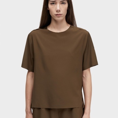 Pessoa com conjunto castanho de camisa e calções com fundo cinzento claro