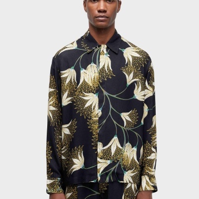 Camisa preta de manga comprida com padrão floral branco e amarelo, colarinho clássico, vista de frente com modelo masculino.