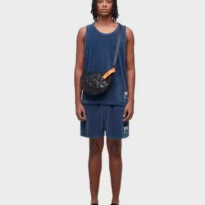 Modelo a vestir conjunto azul de alças e calções aveludados com mala tiracolo preta acolchoada