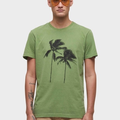 Camiseta verde com estampa de palmeiras e modelo com óculos de sol laranja