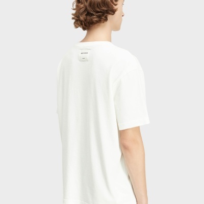 Pessoa de costas com t-shirt branca e cabelo castanho ondulado.