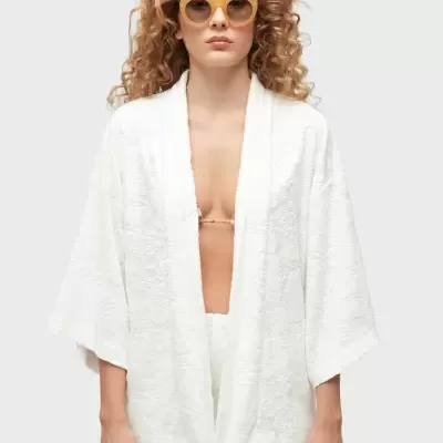 Casaco branco texturizado de manga larga, usado com calções e óculos de sol