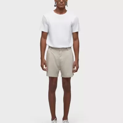 Homem com t-shirt branca, calções bege, sapatilhas brancas e óculos de sol amarelos