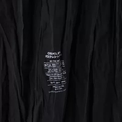 Etiqueta impressa em tecido preto com instruções de lavagem e composição