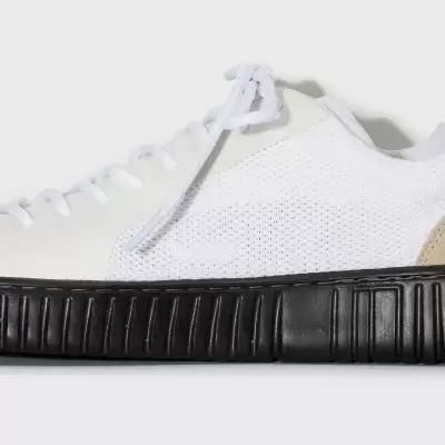 Ténis branco com sola preta texturada e laterais em tecido