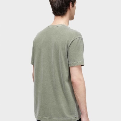 Homem visto de costas com t-shirt verde claro e calças pretas
