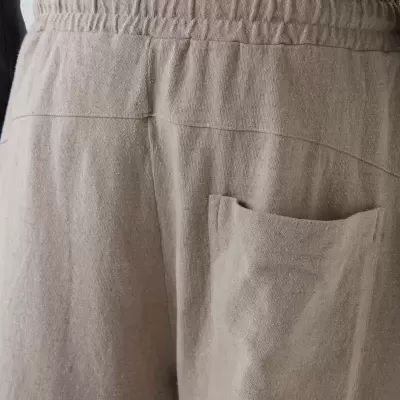 Calças bege claro com elástico na cintura e bolso traseiro num tecido macio.
