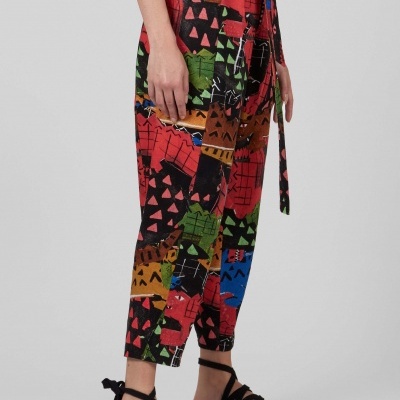Calças coloridas com padrão abstrato usadas com sandálias pretas