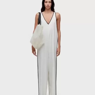 Macacão branco comprido com linhas pretas e bolsa branca