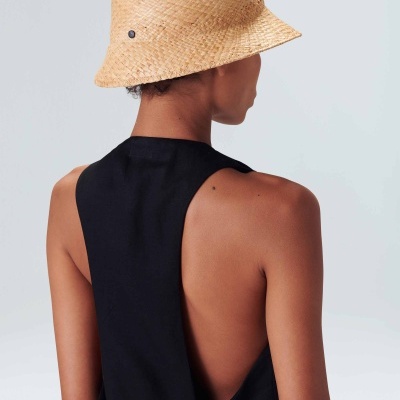 Chapéu de palha bege trançado tipo pescador e mulher de costas com roupa preta