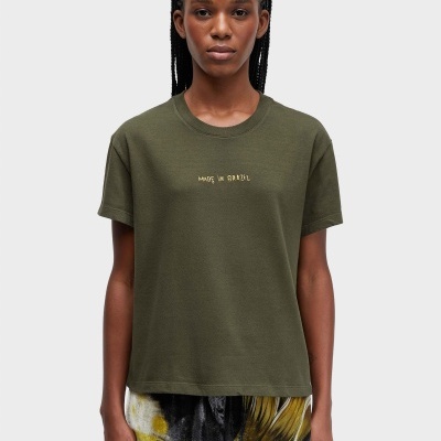 Mulher com t-shirt verde MADE IN BRAZIL e peça inferior estampada azul e amarela